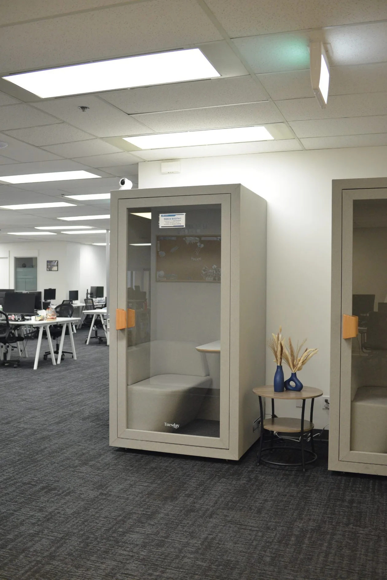 Freestanding acoustic phone booth beside the open office workstations