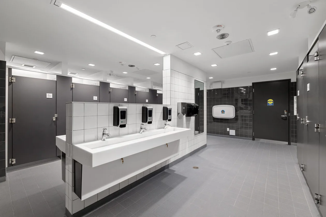 Washroom vanity run with trough basins and privacy stalls