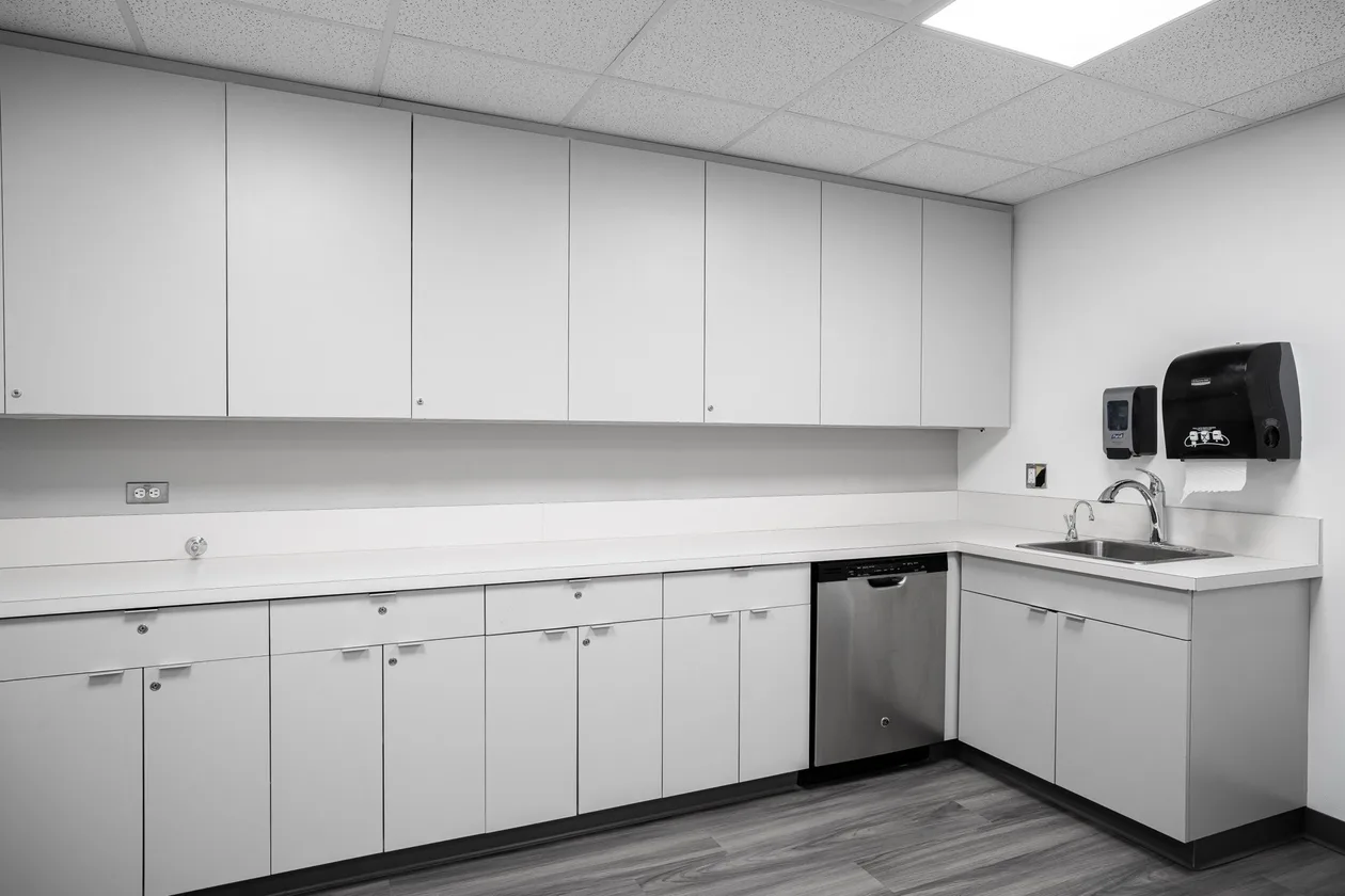 Staff kitchen with white millwork, stainless sink and under-counter dishwasher