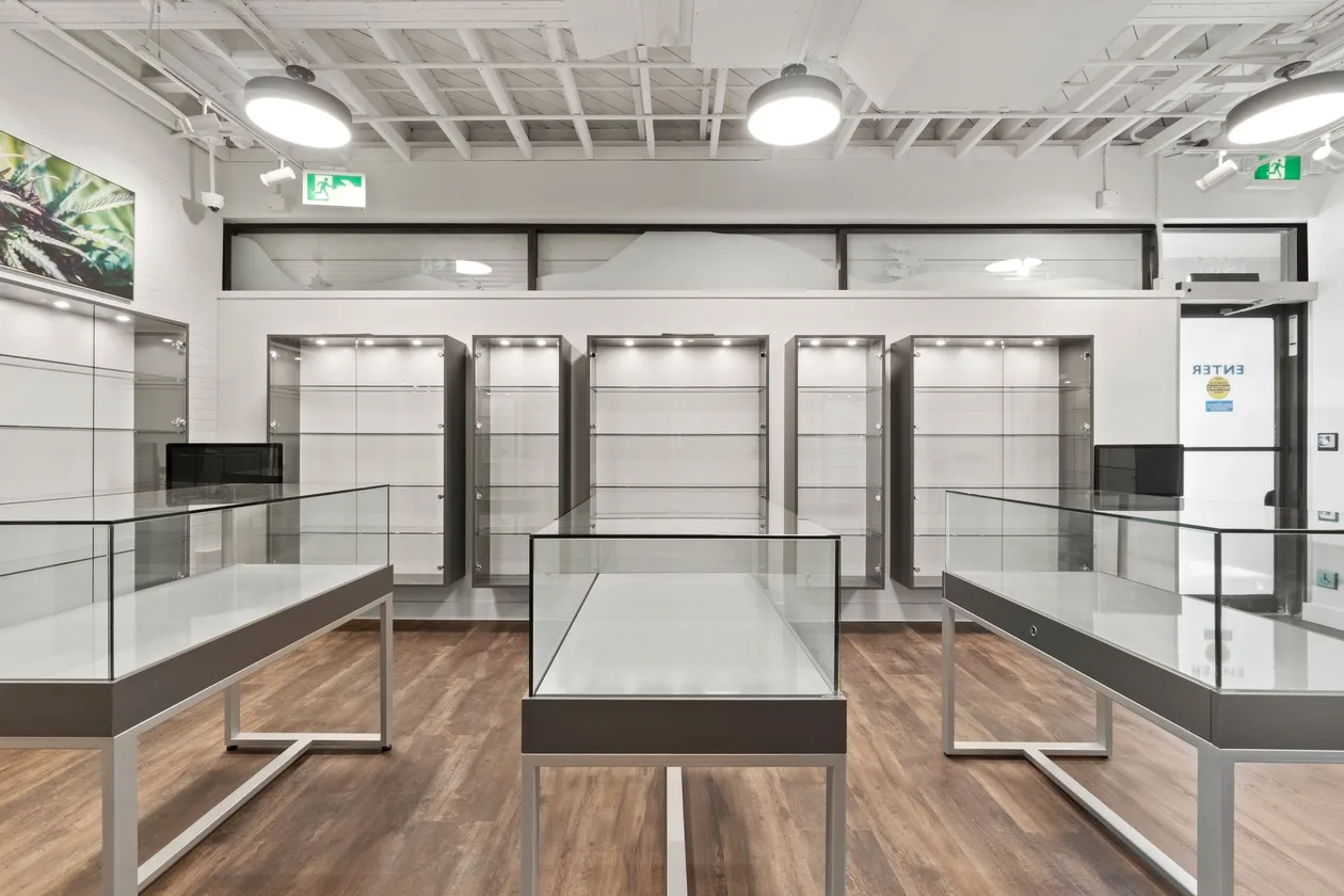 Central display island and illuminated wall shelving on timber plank flooring