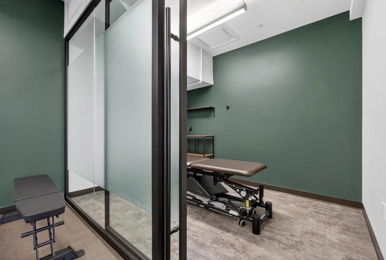 Glazed treatment bay with therapy table and green feature wall