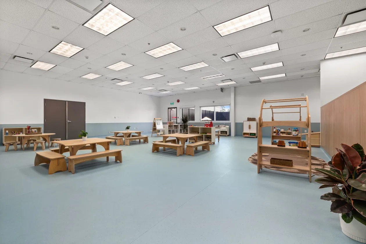 Surrey Childminding childcare fit-out — open play room with timber play furniture on blue resilient sheet flooring