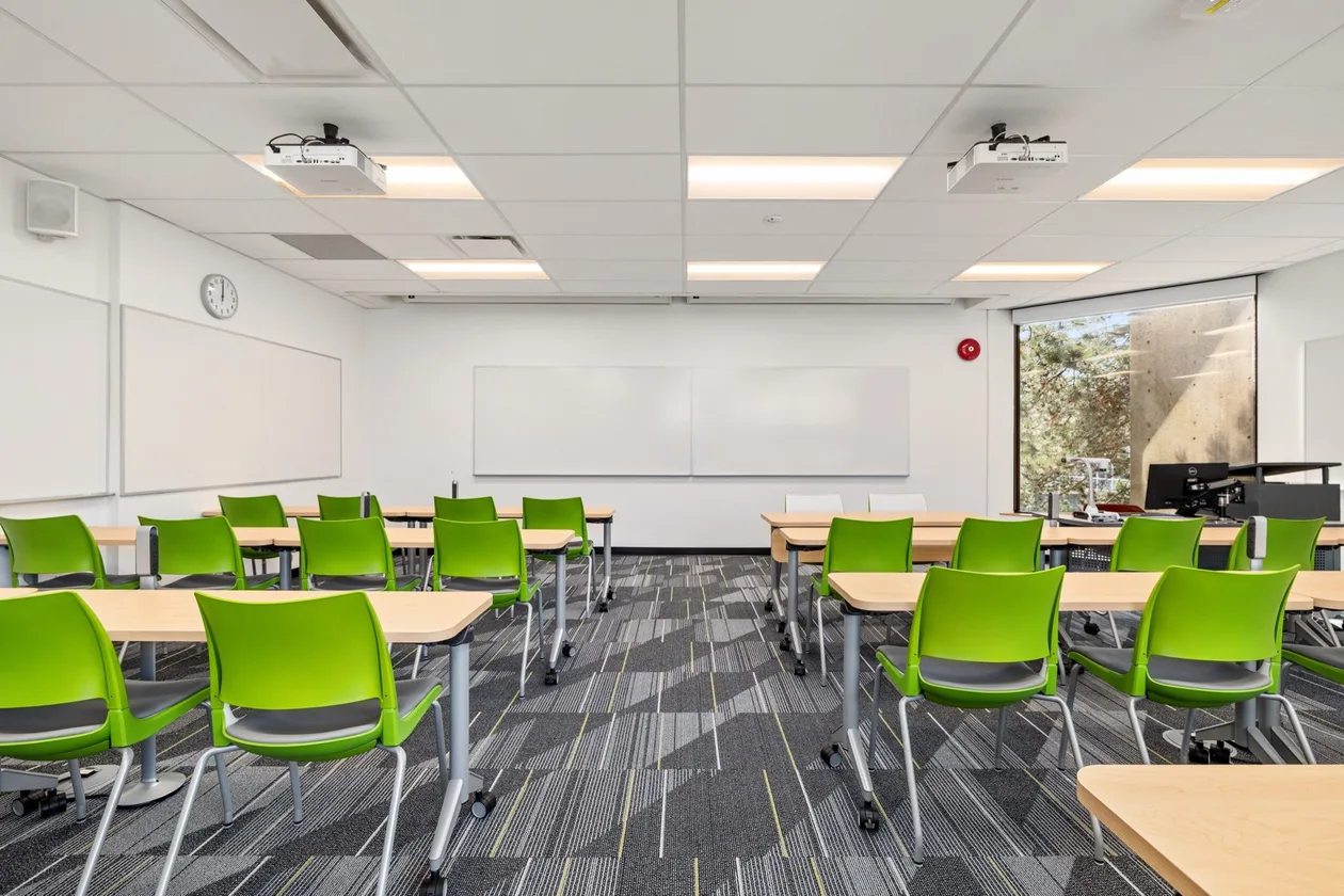 Classroom with green stacking chairs, whiteboard wall and ceiling projector