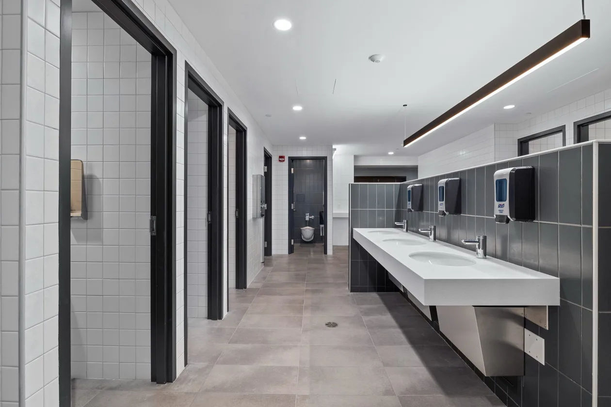 Long vanity run under a linear light with the stall corridor beyond