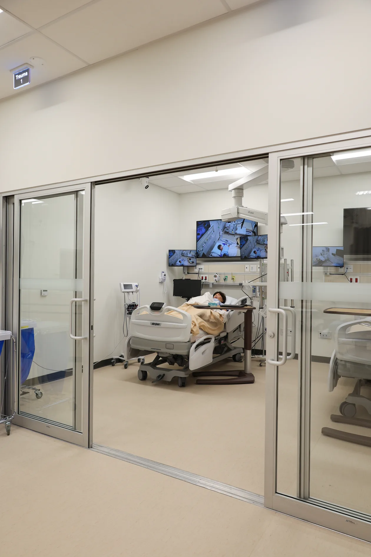 UFV Nursing Simulation Lab — glazed sliding entry to a simulation suite, patient bed and monitor wall beyond, Chilliwack BC
